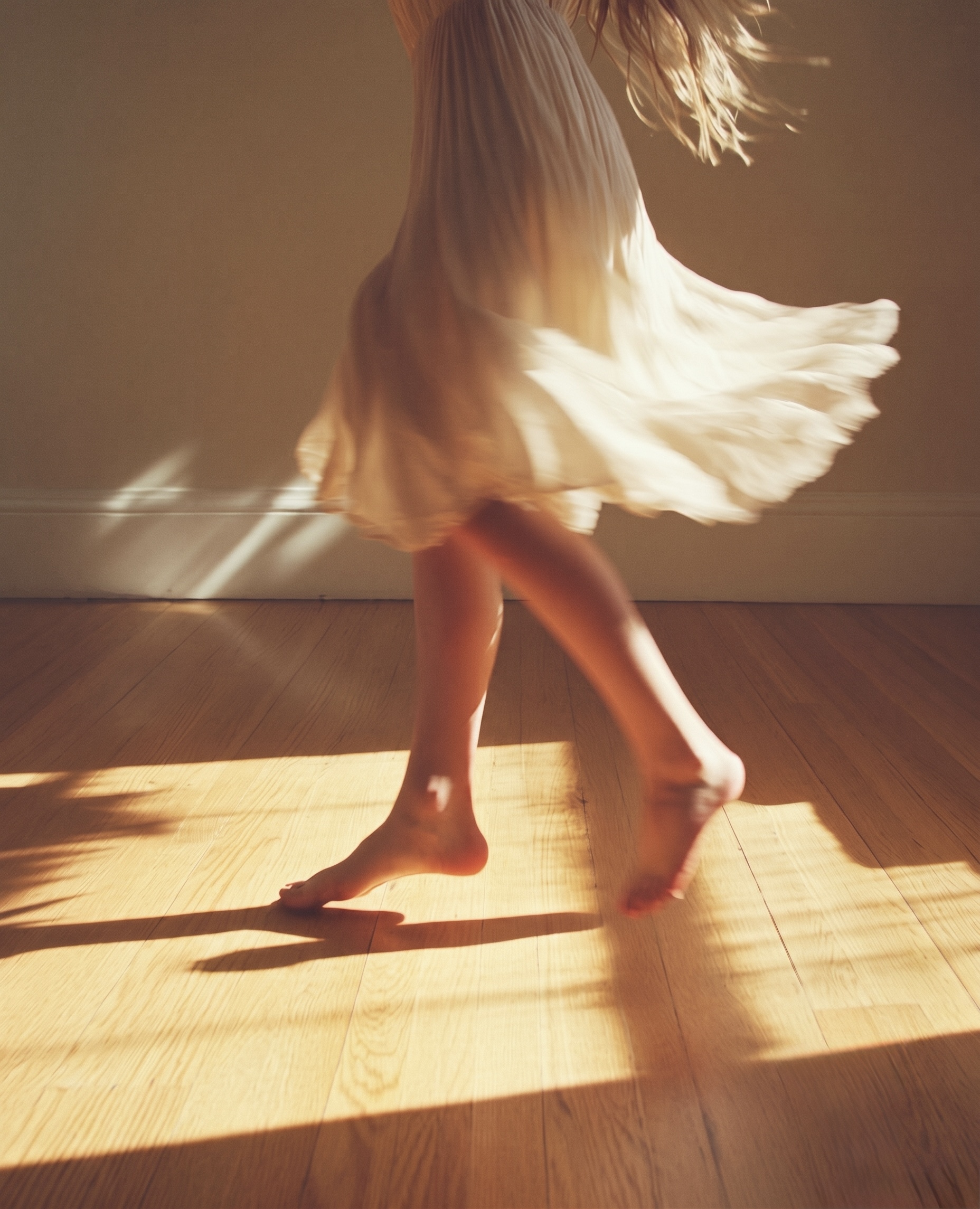 A woman in a white dress moving freely in sunlight on a wooden floor
